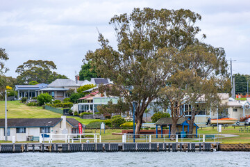 Waterfront homes line the peaceful shoreline of Paynesville, a quintessential Australian laid-back coastal town in regional Victoria. The wooden jetty extends over the calm waters near the town center