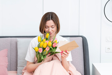 A young beautiful girl received a bouquet of flowers and a congratulatory letter on a wonderful...