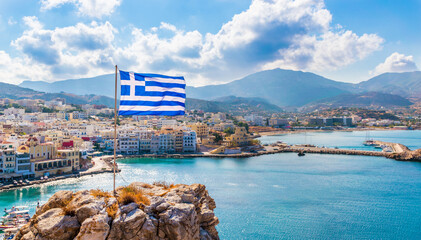 Fototapeta premium Panoramic view of Pigadia bay, town and harbor with Greek flag, Karpathos Island, Greece