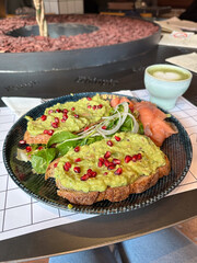 Avocado toast topped with pomegranate seeds, fresh greens, and smoked salmon