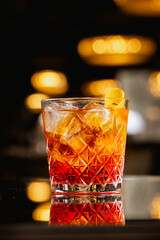 Negroni drink. Close up photo with a glass with negroni cocktail made of gin and vermouth on the glass table of a pub. Cocktail alcohol drinks.