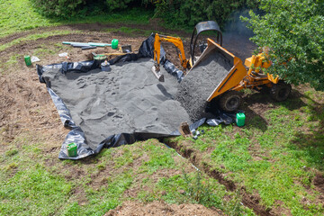 Installing a sand and gravel filter bed for a domestic septic tank using  a front end loader  and...