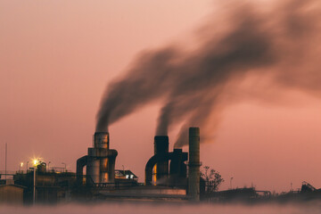 Toxic smoke from chimneys of industrial factories at night. Atmospheric pollution, environmental...