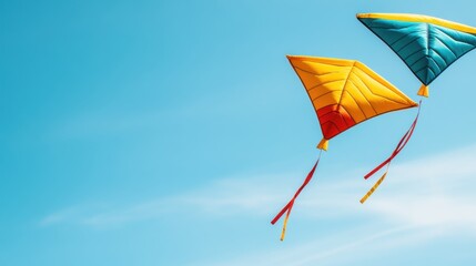 Two colorful kites soar in a clear blue sky, showcasing a vibrant contrast against the serene backdrop.