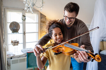 Young man musician teaching a teen girl to play violin. Education music instrument happiness concept
