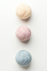 Fototapeta premium Pastel Yarn Balls: Three perfectly aligned yarn balls in soft pastel hues of beige, pink, and blue, offering a delicate and calming aesthetic. 