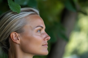 Fototapeta premium A side profile of a beautiful woman surrounded by lush green leaves, exuding tranquility, confidence, and a strong connection to both nature and self.