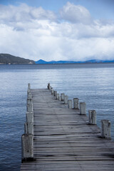 Dock in lake, Patagonia lake, mountains in the background, calm water horizon, blue sunset