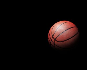 Obraz premium A basketball illuminated against a dark background, emphasizing its texture and shape.