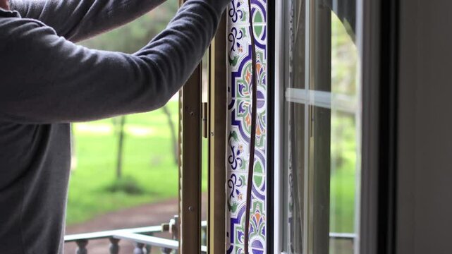 Man installing weatherstripping on a window frame to improve insulation and prevent drafts. Home maintenance, energy efficiency, and DIY repair concept in a bright interior.