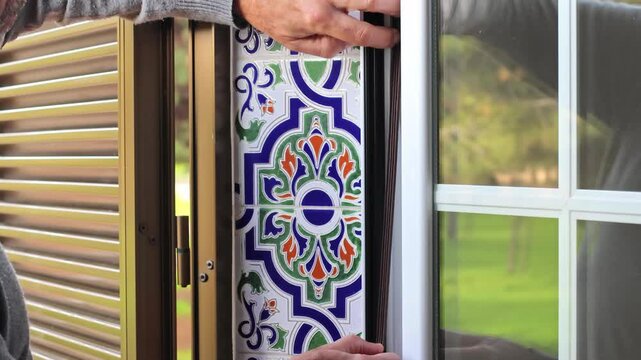Man installing weatherstripping on a window frame to improve insulation and prevent drafts. Home maintenance, energy efficiency, and DIY repair concept in a bright interior.