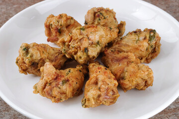 Fried chicken in a white ceramic plate on a wooden table.