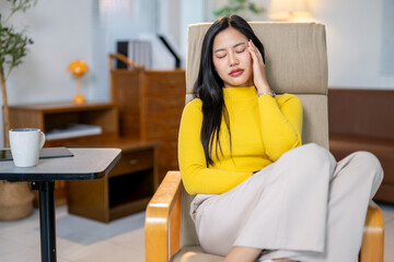 Obraz premium A woman in a yellow sweater is sitting in a chair with her head in her hands