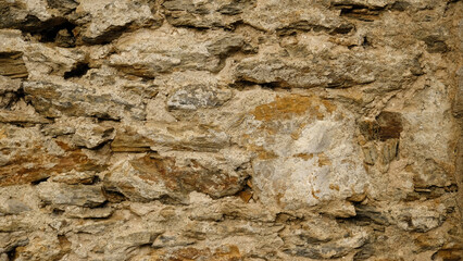 Texture of beige stone wall with rough masonry and uneven surface. Smooth, cracked surface. Old castle wall of stone different shape. Pattern with neutral colors. Minimal, stylish, trend concept.