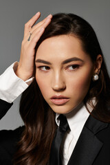 A beautiful young woman showcases her long brown hair and stylish outfit in a sleek studio.