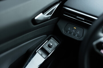 Window control buttons in modern luxury electric car. Car leather interior details of door handle with windows controls and adjustments. Car window controls. Door handle with power window control