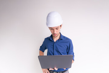 Portrait of young architect wearing white helmet, working with laptop. Isolated on white background.