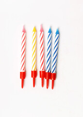 Five unlit colored candles for a birthday cake lie on a white background. Preparation for the holiday