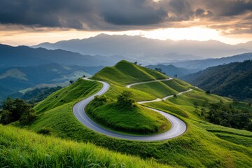 A scenic mountain road with a zigzagging path, surrounded by lush green forests and dramatic peaks