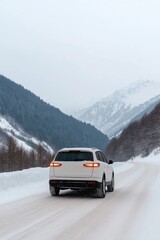 Naklejka premium A white car is driving down a snowy road in the mountains. The car is surrounded by snow and the mountains in the background. The scene is peaceful and serene, with the car moving slowly