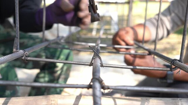 The hands of construction workers using using steel wire to bind steel bars Construction concept