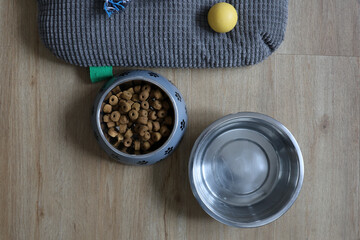 Une gamelle d'eau et de croquette pour chien à coté d'un cousin