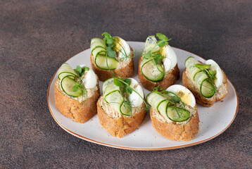 Bruschetta with tuna pate, egg and cucumber on white plate