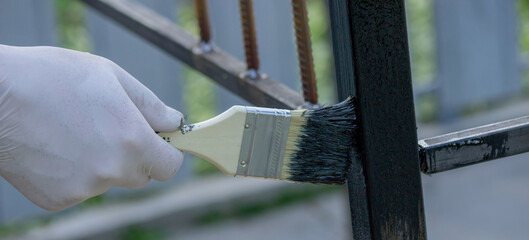 a man paints metal with black paint with a brush. Selective focus