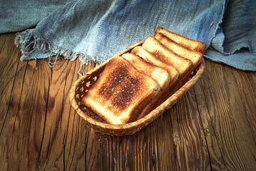 A stack of toasted bread on a wooden board. The bread is toasted and has a crispy texture. The wooden board is brown and has a natural texture. Warmth and comfort concept