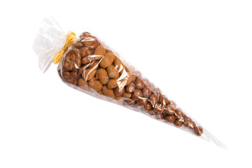 Mixed nuts like almonds, peanuts or dried fruit like bananas melted in chocolate and cocoa wrapped as a gift in plastic bag with yellow ribbon separated on the white background.