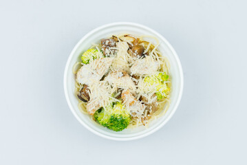 pasta with cream sauce, broccoli, parmesan and chicken in a white plate, isolated