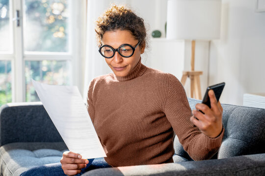 Black woman portrait at home holding document and mobile phone