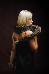 Sexy blonde holding a snake. Photo shoot with an anaconda