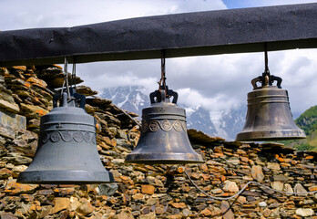 Obraz premium Traditional bronze bells hanging in front of a stone wall
