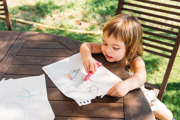 Happy Girl Enjoys Drawing Outdoors on a Sunny Day at a Garden Table