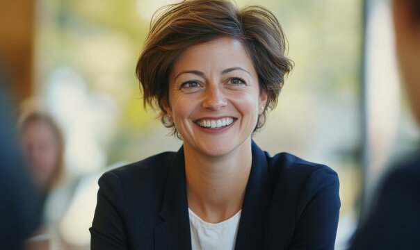 professional woman smiles warmly during meeting, showcasing confidence and positivity. Her engaging expression reflects supportive work environment