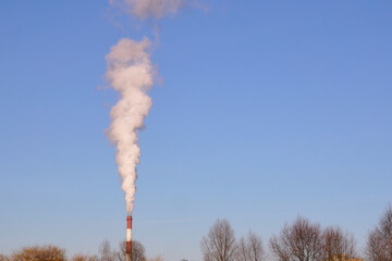 Thick white smoke is coming from the chimney of an industrial enterprise, the concept of air...