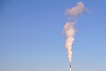 Thick white smoke is coming from the chimney of an industrial enterprise, the concept of air...