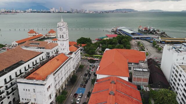 Aerial panorama capturing heritage clock tower alongside historic ferry terminal situated in george town, penang, malaysia