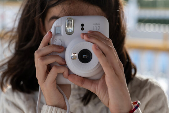 Jaen, Spain - Jan 22, 2025: Cute little happy girl with picture camera Fujifilm Instax Mini 12