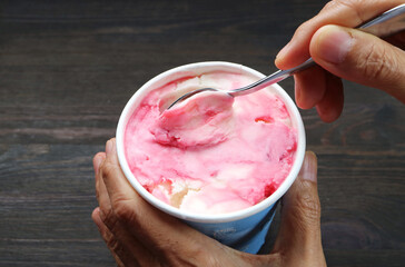 Hand scooping delectable strawberry yogurt ice cream with a spoon