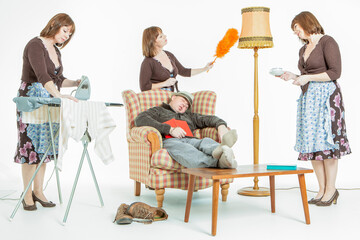 Multitasking Wife. An archaic stereotype of a domestic scene with a sleeping husband surrounded by...