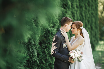 Happy wedding couple charming groom and perfect bride posing in park