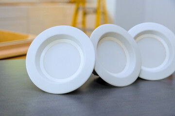 Simple white LED ceiling lights are neatly arranged on dark countertop in contemporary kitchen filled with natural light.