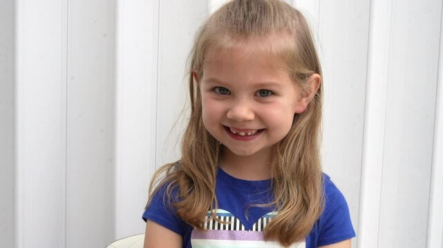 Cute Caucasian preschool girl wiggling her baby tooth with her finger which is ready to fall off. Dentistry concept. Happy healthy child about to lose a tooth