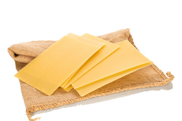 Durum wheat pasta, lasagna on a jute bag, close-up, isolated on a white background.