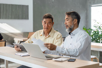 Obraz premium Experienced businessmen analyzing reports and discussing strategy in a contemporary office space