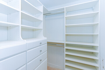 Bright, empty closet showcasing white shelves, drawers awaiting organization, storage solutions.