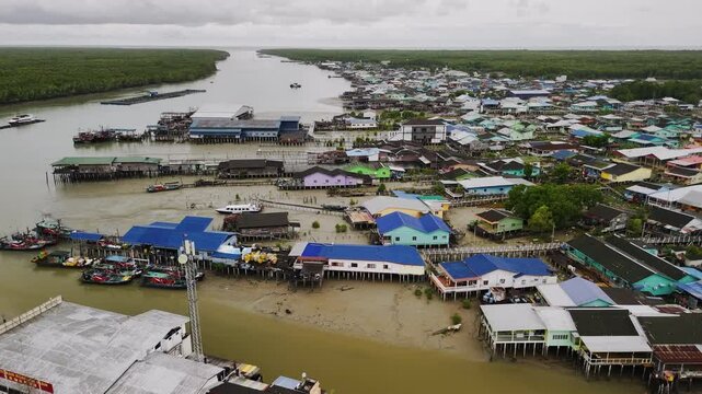 Wooden fishing vessels anchored alongside weathered piers, revealing coastal malaysian settlement's maritime lifestyle under overcast atmospheric conditions