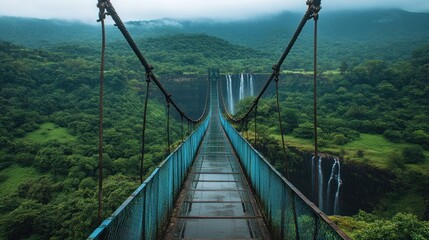 Obraz premium Suspension bridge over lush valley with waterfalls.